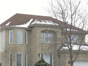 A large brick house with snow on the roof.