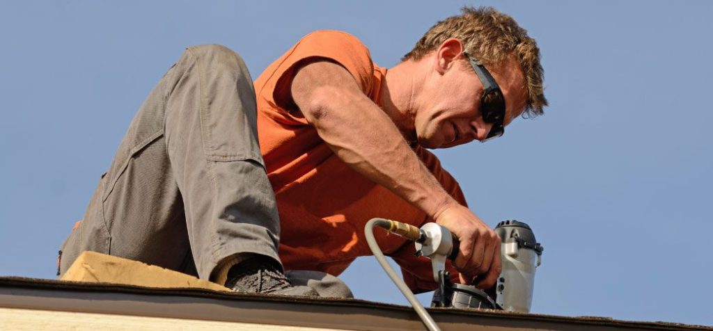 A man working on the roof of his house.