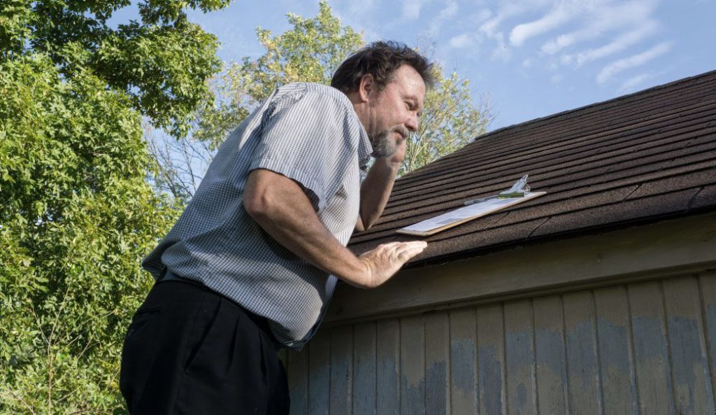 A man standing on the side of a house holding something.