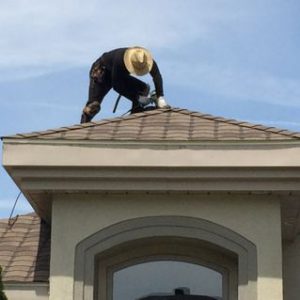 A man on top of a roof fixing something.